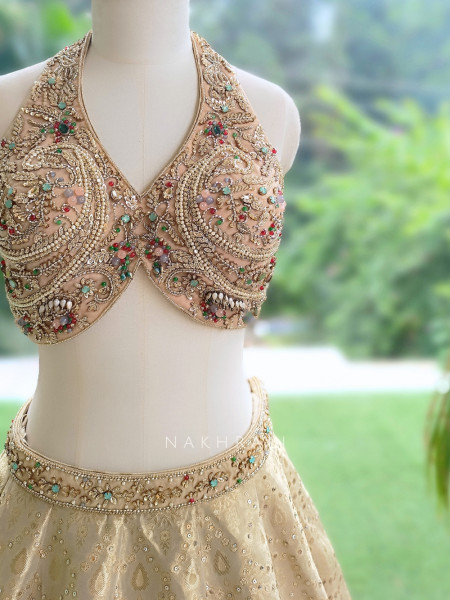 Kanakriti Beige Banarasi Brocade Silk Lehenga Set With Jewel Embellished Halter & Zari Work