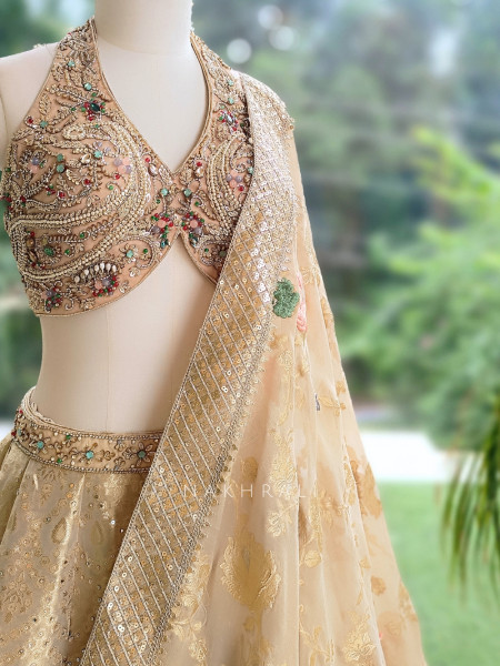 Kanakriti Beige Banarasi Brocade Silk Lehenga Set With Jewel Embellished Halter & Zari Work