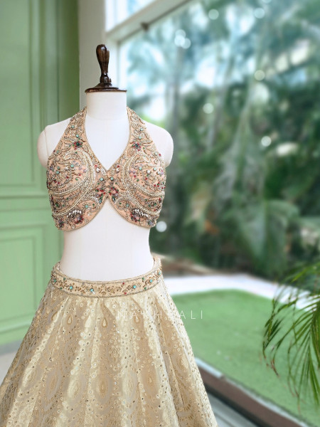 Kanakriti Beige Banarasi Brocade Silk Lehenga Set With Jewel Embellished Halter & Zari Work