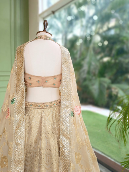 Kanakriti Beige Banarasi Brocade Silk Lehenga Set With Jewel Embellished Halter & Zari Work
