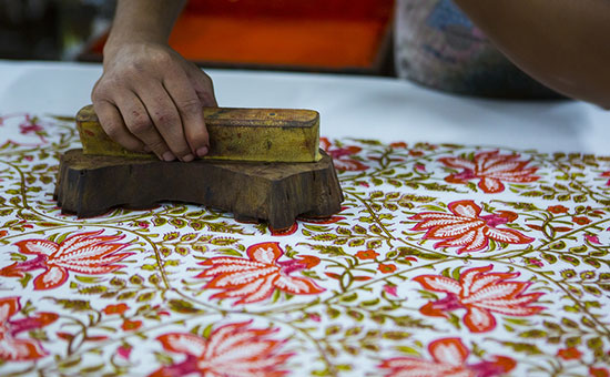 Artisan pressing a wooden block onto fabric during hand block printing