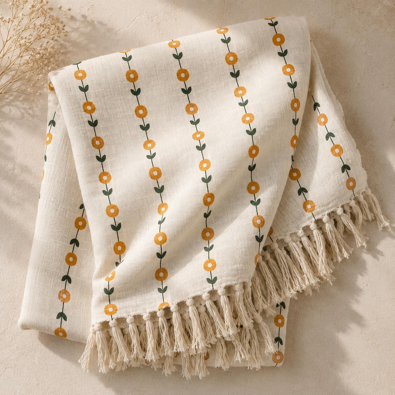 Folded cream cotton throw with marigold vine print and hand-knotted tassel fringe