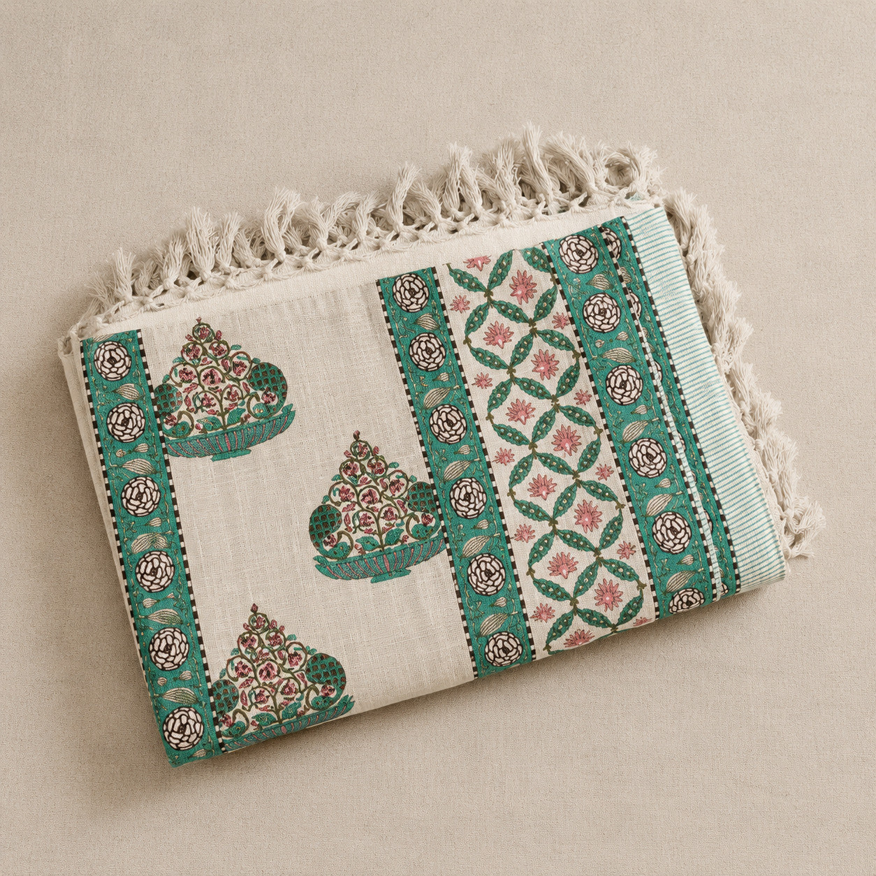 Folded green and cream cotton throw showing floral urn print and geometric trellis border