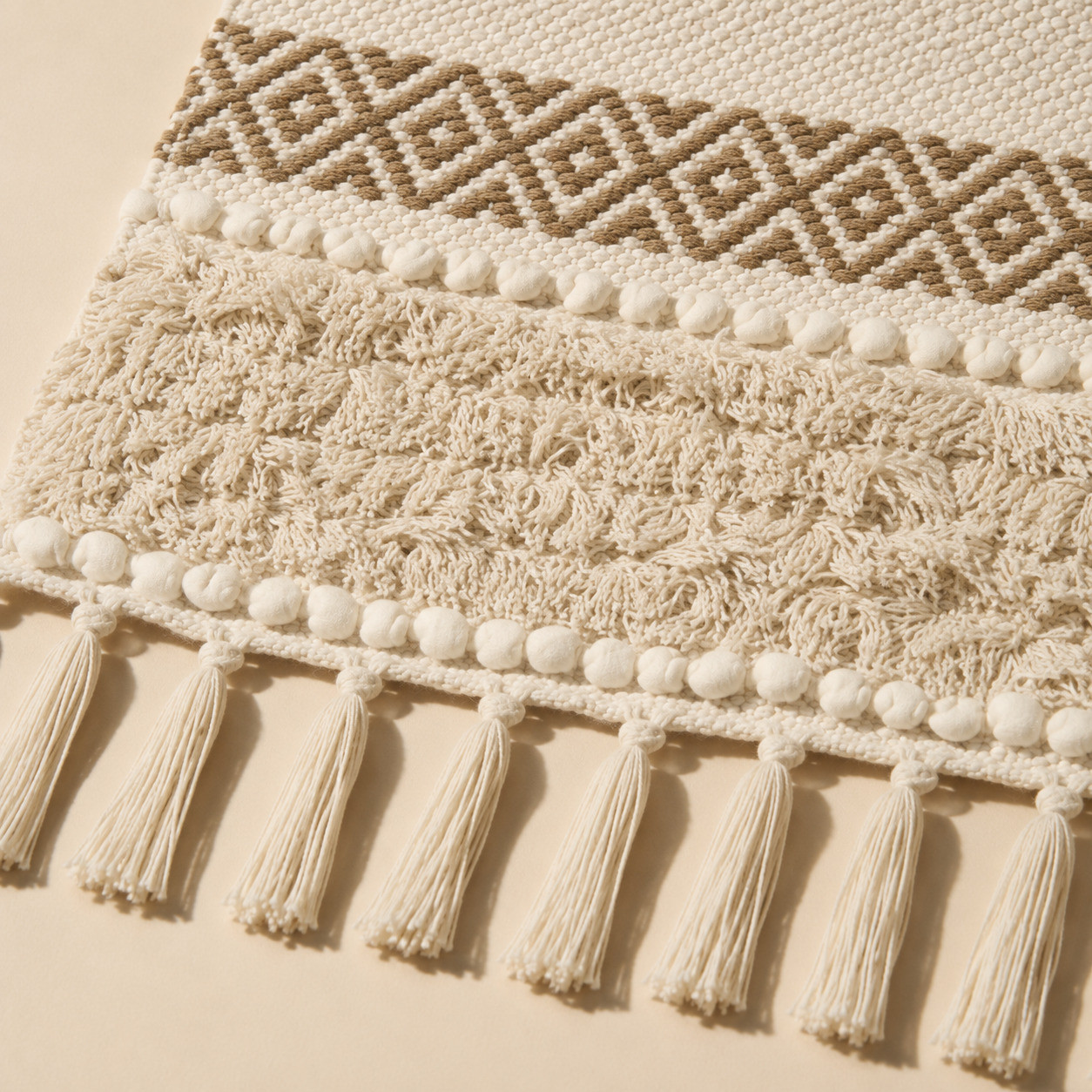 Close-up of tufted textured band and fringe tassels on ivory beige table runner