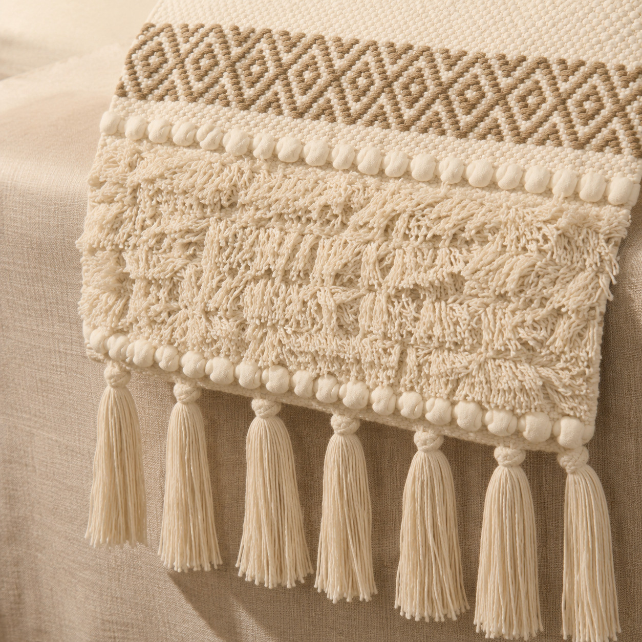 Textured tufted section and hand-knotted tassels on beige boho table runner