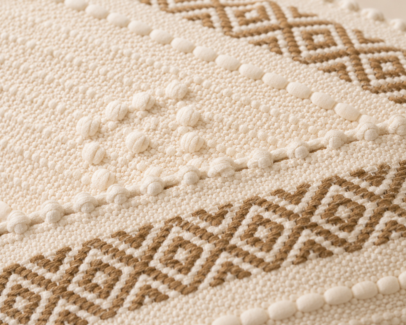 Close-up of diamond zigzag weave and pom-pom trim on boho cushion cover