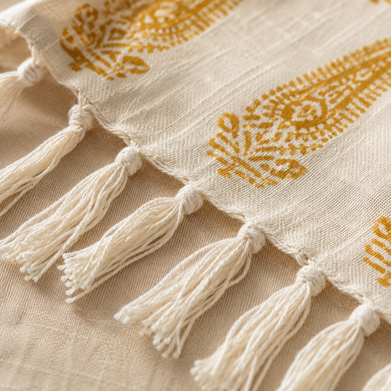 Close-up of hand-knotted tassels on mustard paisley cotton handblock print throw