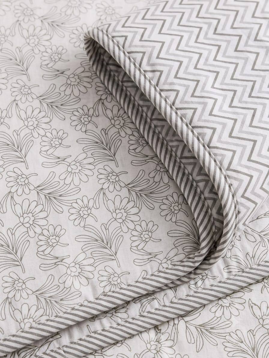 Close-up of folded cotton dohar corner showing daisy floral print chevron reverse and striped corded piping