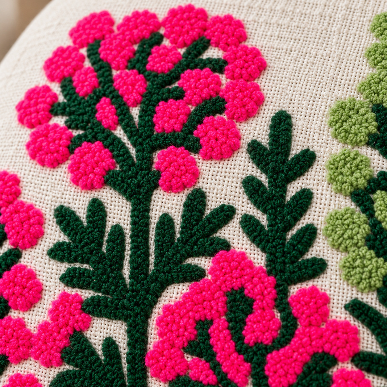 Close-up of hand embroidered magenta pink flowers with dense thread stitch dark green leaves
