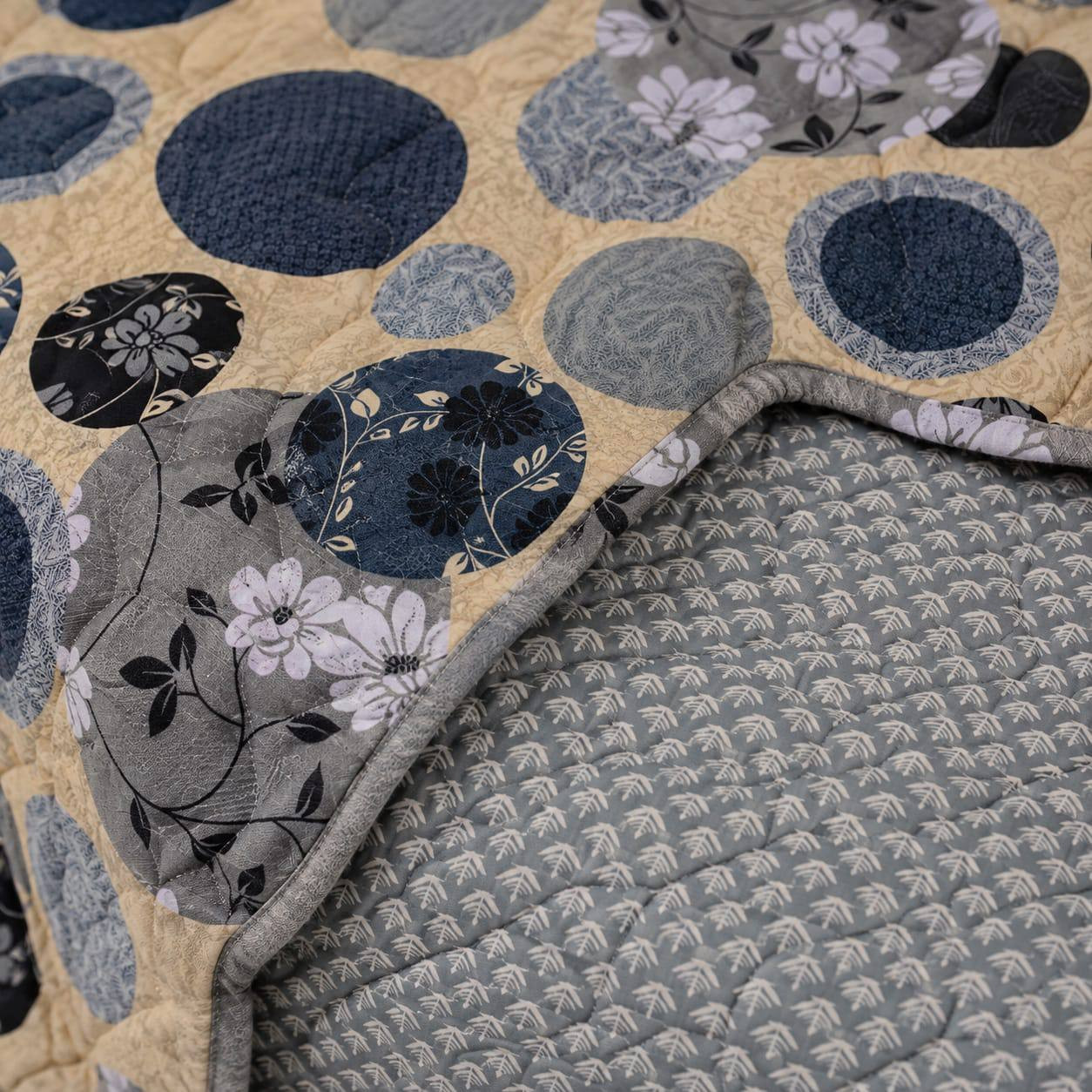 Close-up of navy gold circle print cotton quilted comforter showing mini floral detailing and reversible grey leaf-print lining