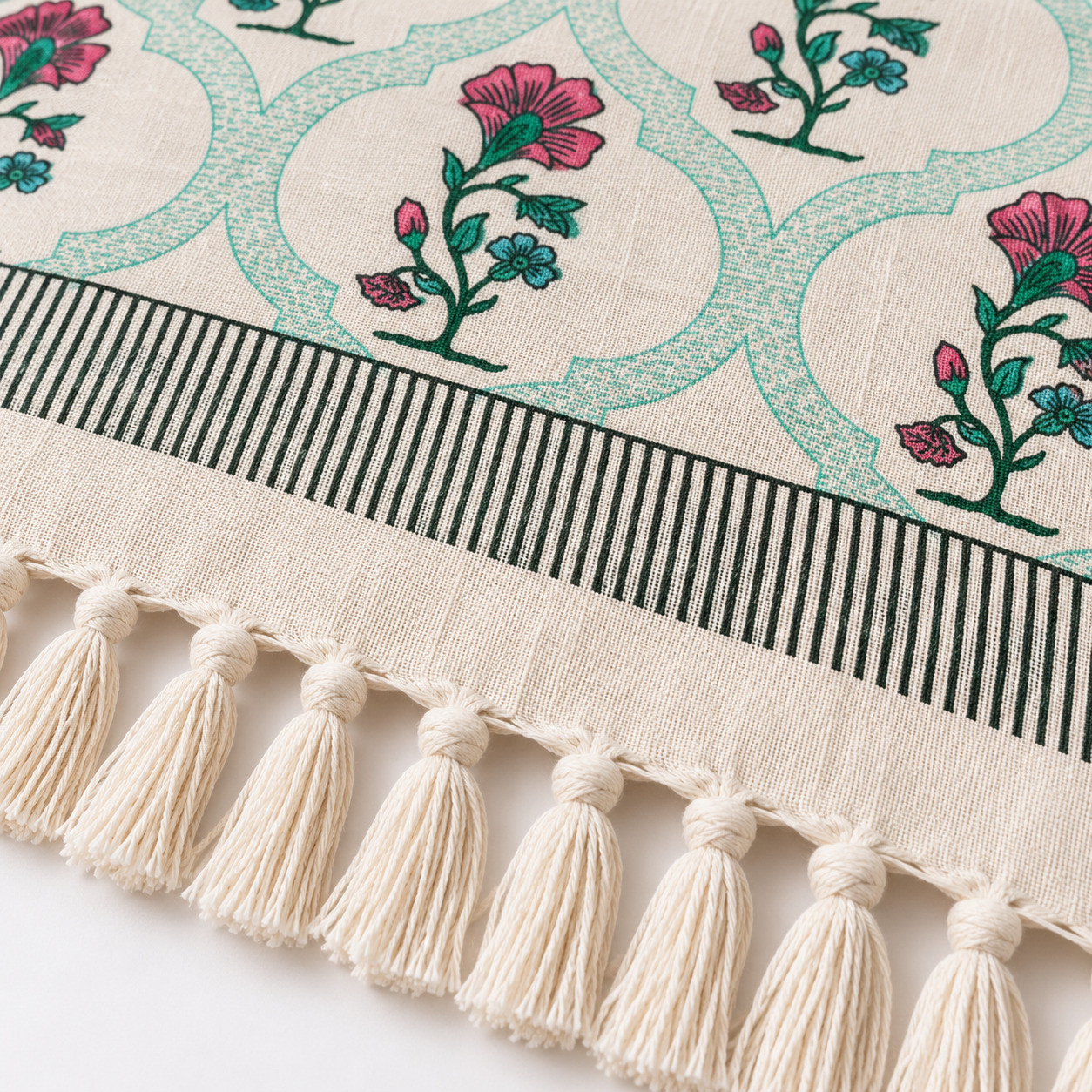 Flat lay of pink blue floral trellis cotton sofa throw with striped border and tassel fringe