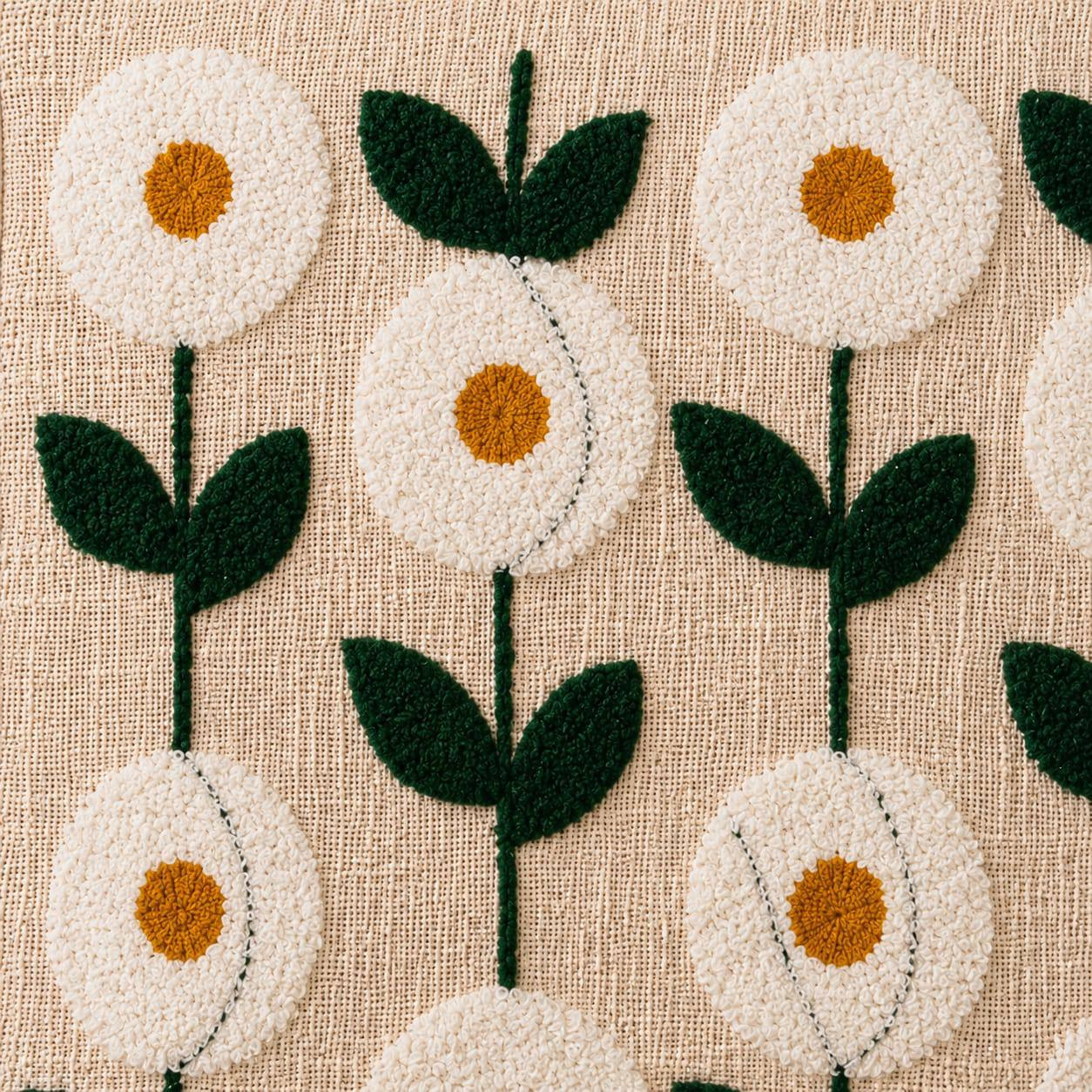 Close-up of hand embroidered daisy motifs on white cotton cushion cover