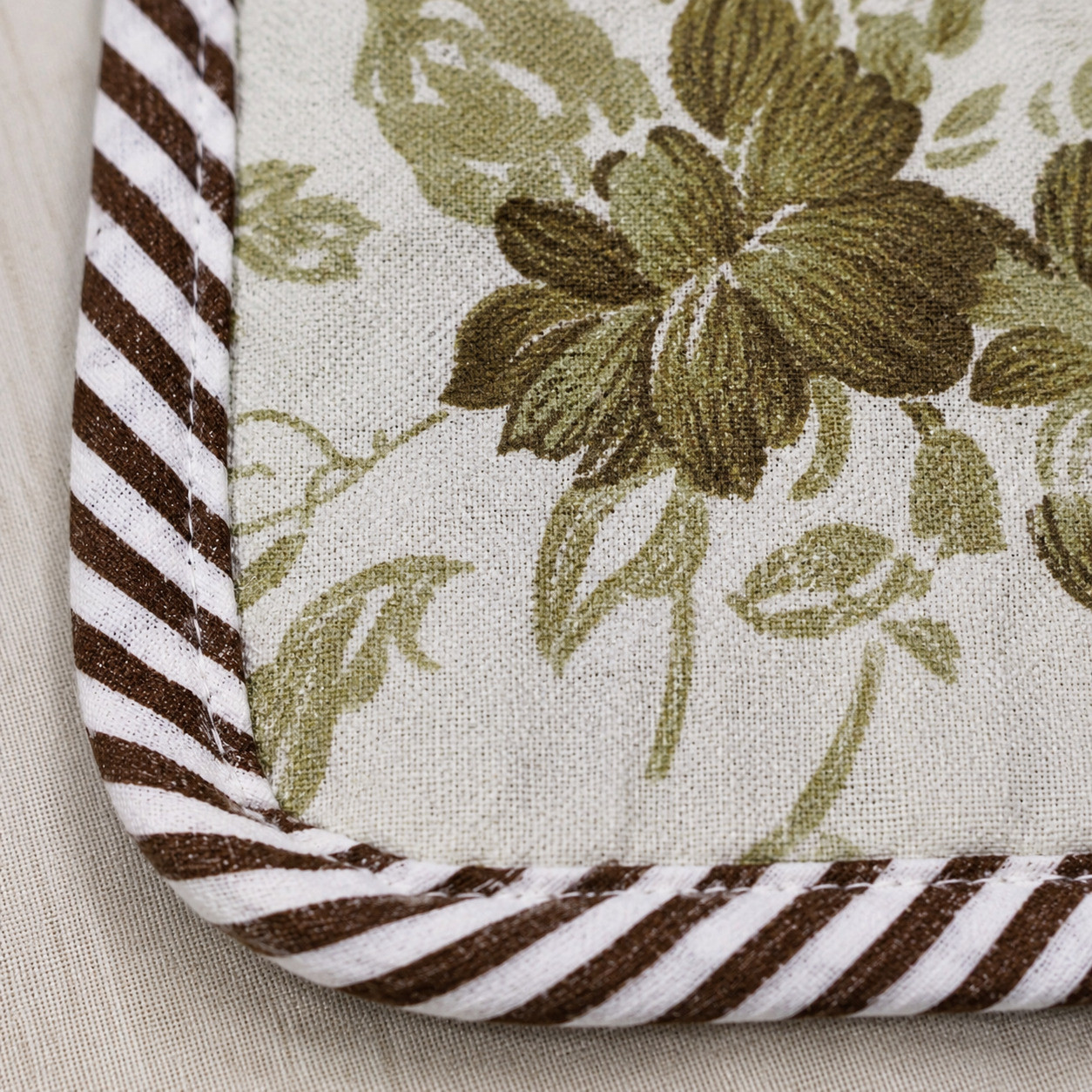 Macro shot of sage green rose print corner with brown