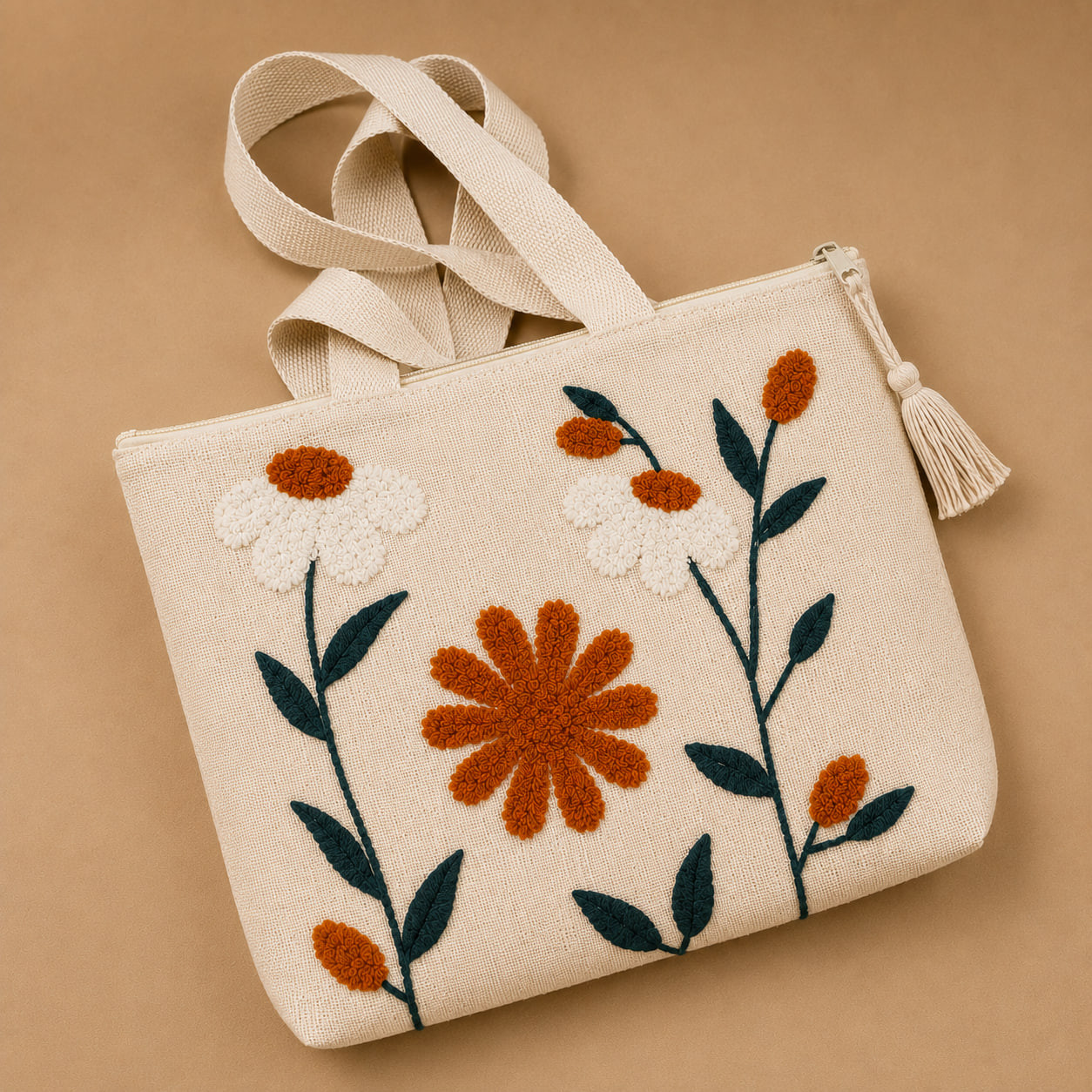 Close-up angle of embroidered rust daisy tote bag showing tassel zip pull