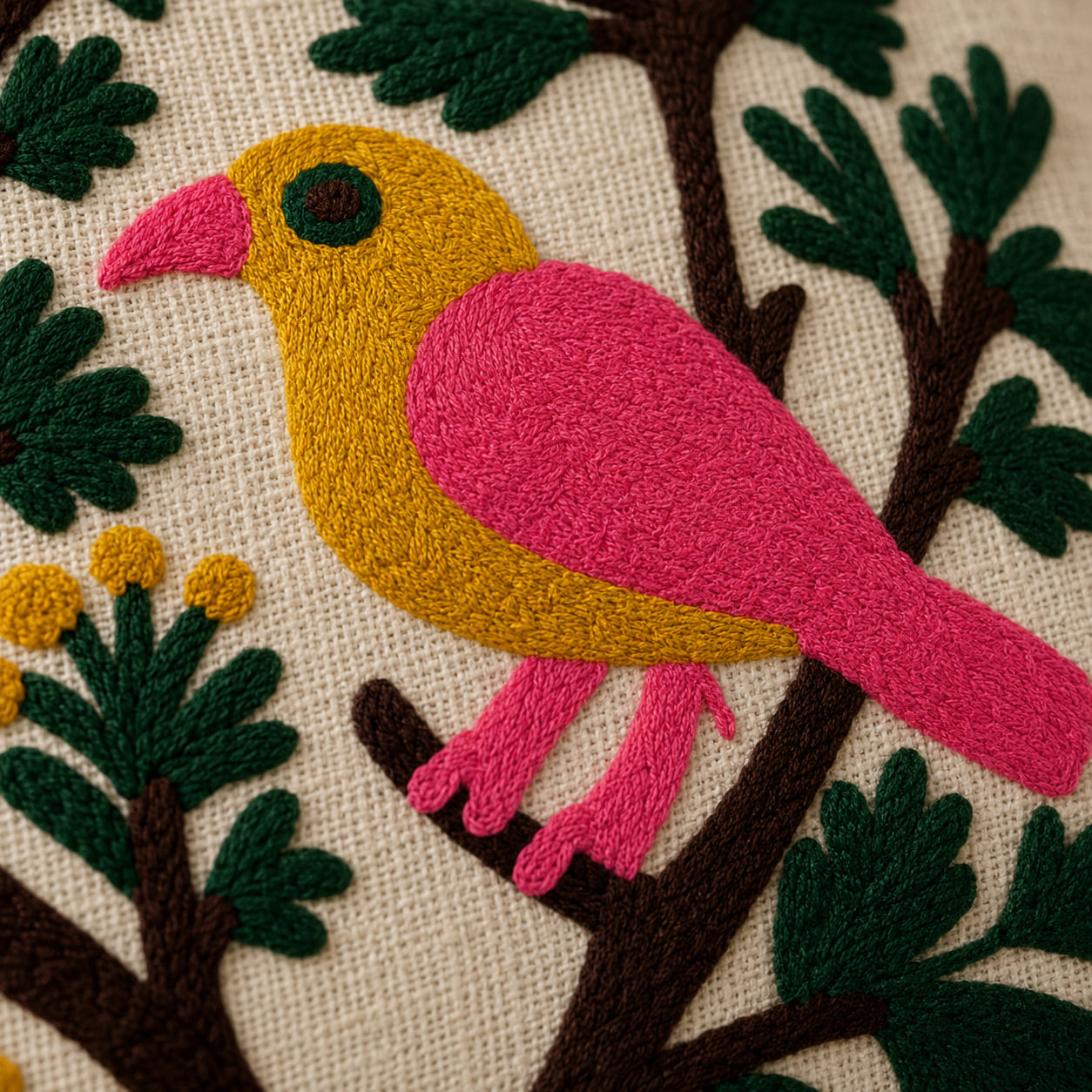 Close-up detail of hand embroidered pink and yellow bird design