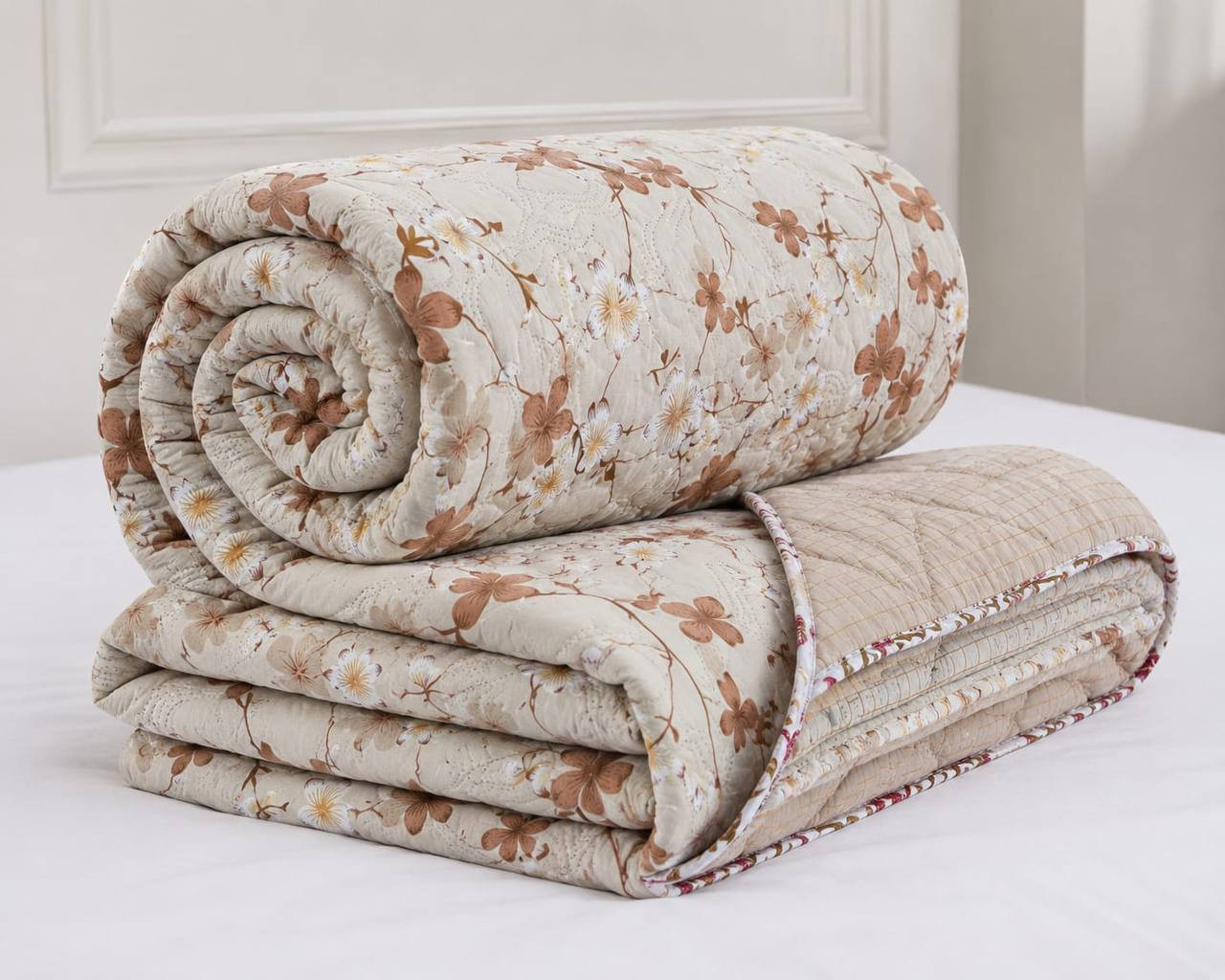 Rolled double bed cotton quilted comforter in blossom branch print with reversible beige checked lining visible